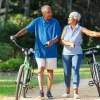 a couple walking bikes under the trees