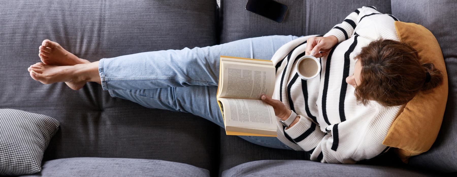 a person lying on a couch reading a book